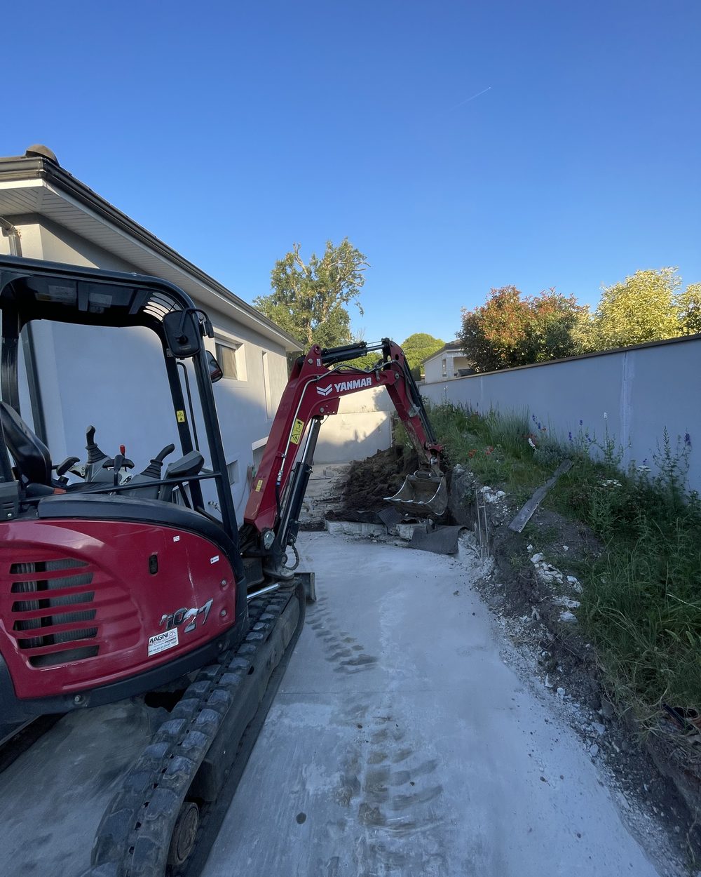 Mini-pelle intervenant sur un chantier de démolition et d'évacuation le long d'une maison