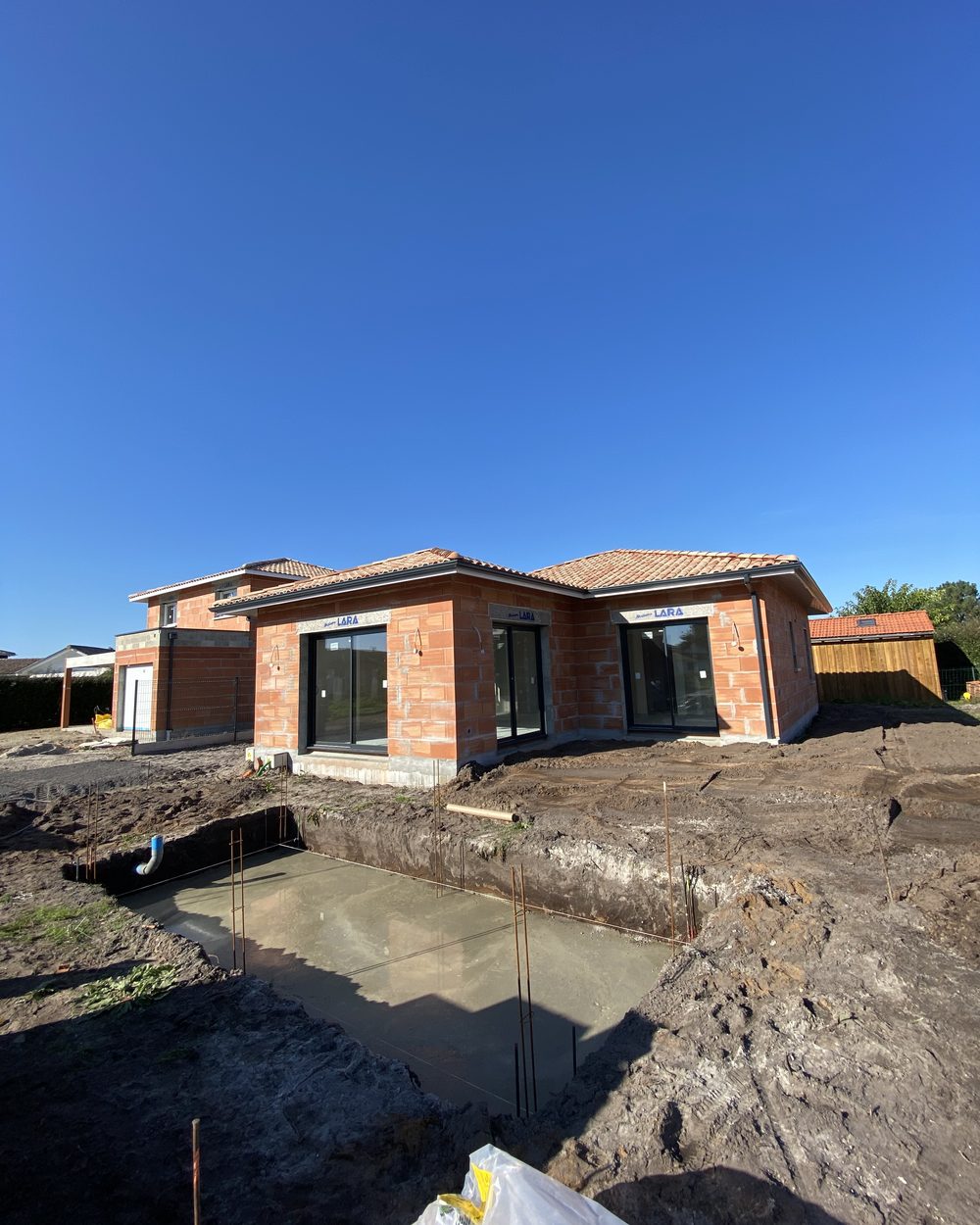Dalle béton coulée en fond de fouille devant une villa en construction