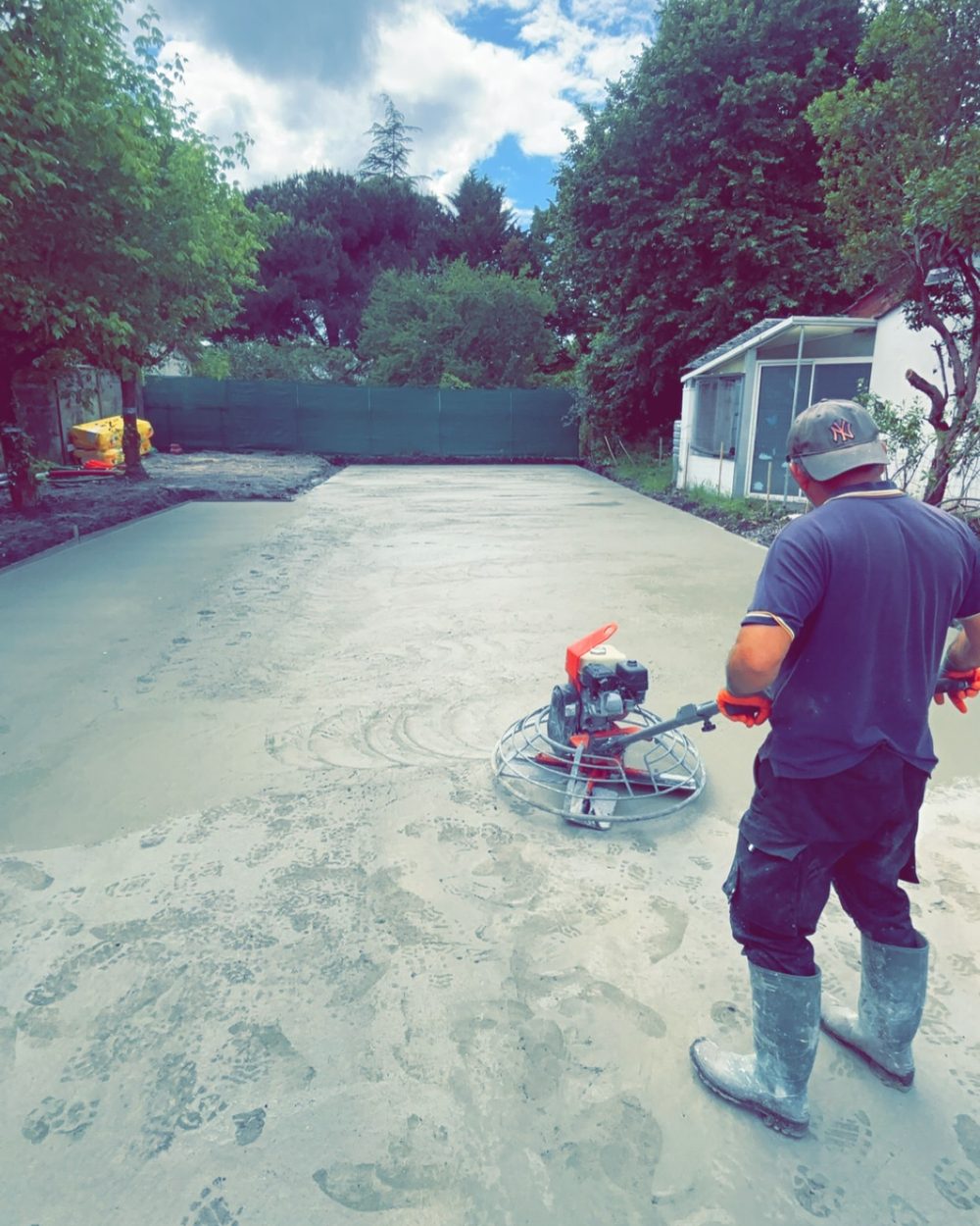Maçon lissant une dalle en béton à l'hélicoptère sur un chantier