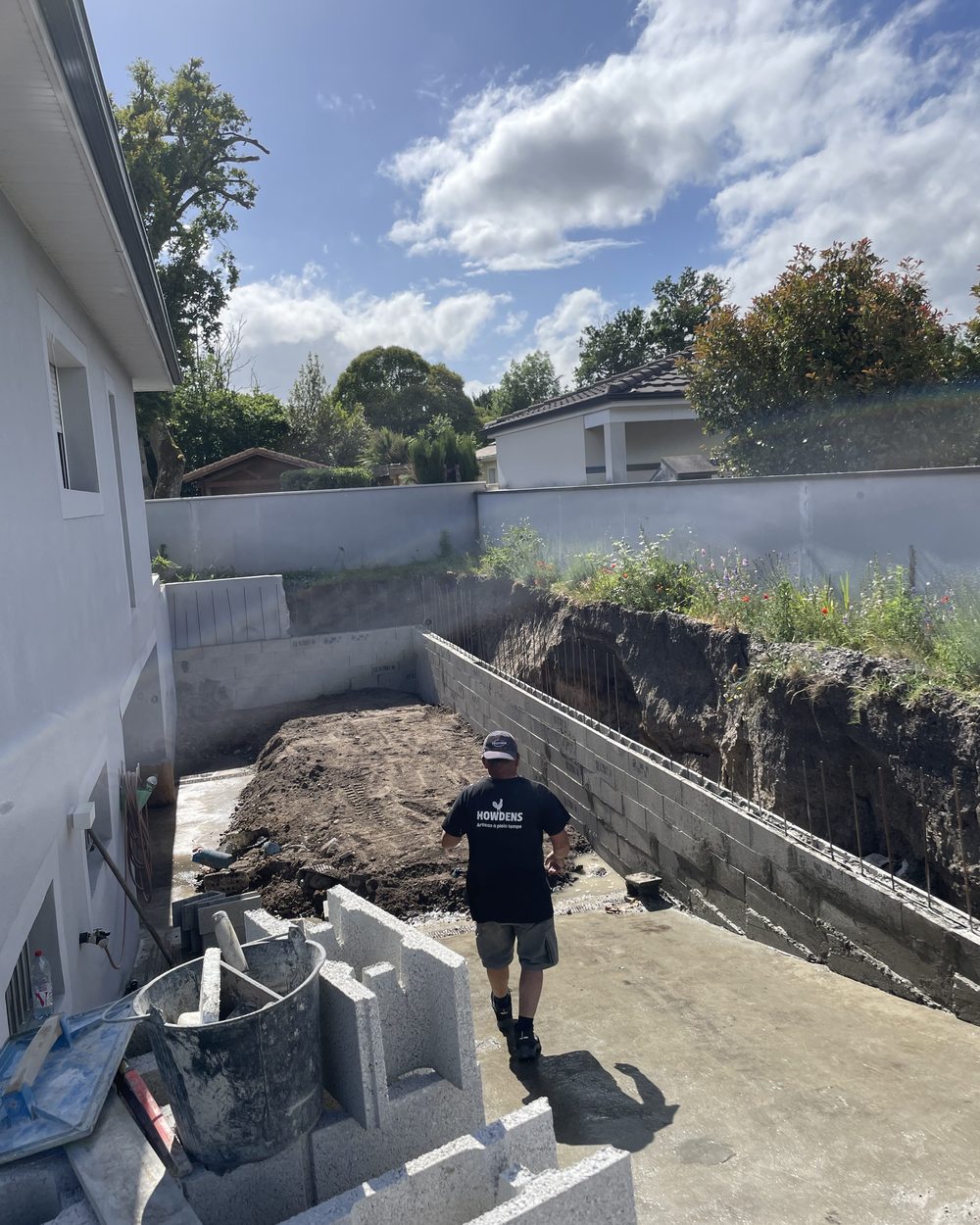 Chef de chantier AQUICONSTRUCTION dans une fouille de piscine avec murs de soutènement